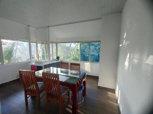 a dining room with a table and chairs and windows at Villoonnickal Homestay in Munnar
