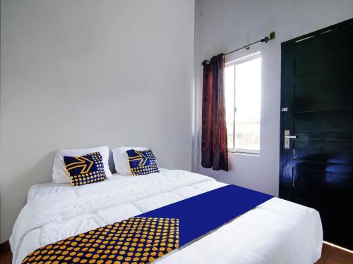 uma cama com almofadas azuis e amarelas e uma janela em SPOT ON 91598 Oklahoma Homestay Syariah em Pekanbaru