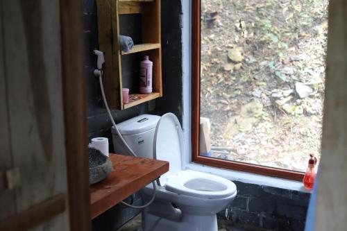 a bathroom with a toilet and a window at Mộc Châu Peachy Garden in An Pon