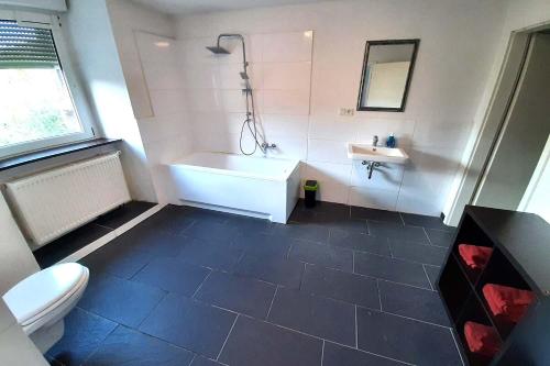 a bathroom with a tub and a toilet and a sink at Spacious Work & Stay Apartments Büdesheim in Büdesheim