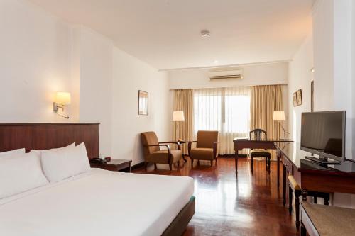 a hotel room with a bed and a flat screen tv at Le Charme Vientiane Hotel in Vientiane