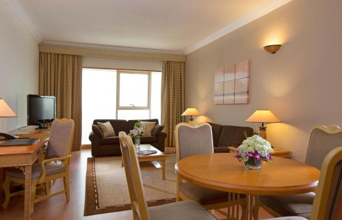 a living room with a table and chairs and a couch at Millennium Plaza Downtown Suites in Dubai