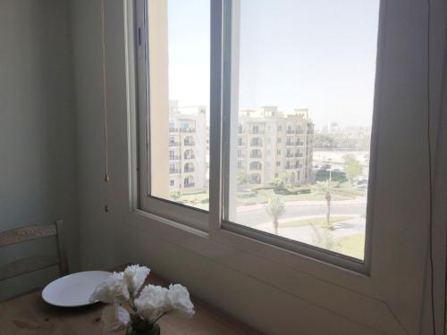 a table with a vase of flowers sitting next to a window at Cozy 1BR Apartment close to Dragon Market and Global Village in Dubai