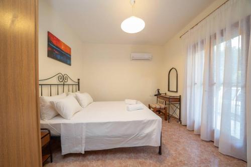 a bedroom with a white bed and a window at Afroditi Holiday Home - Blue Apartment in Svoronata