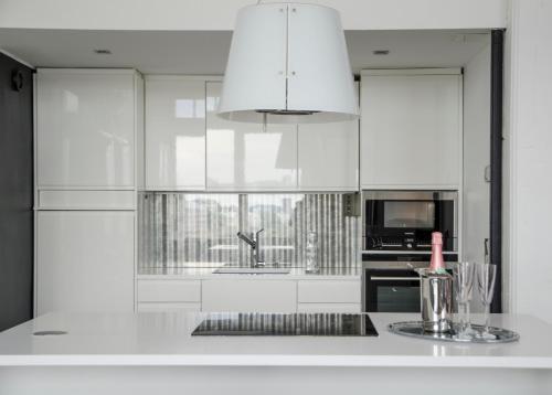 a kitchen with white cabinets and a sink at Upea loftsuite, järvinäkymä, wifi, sauna & spa in Tampere