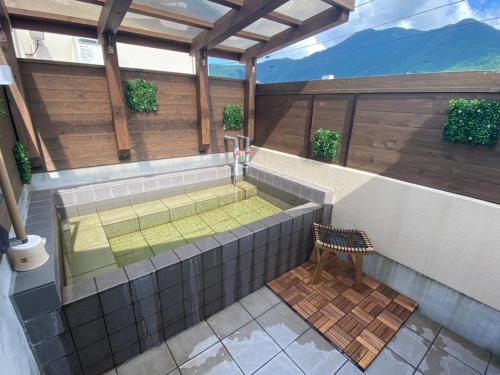a building with a hot tub and a chair at ETAVIA Yufuinekimae in Yufuin