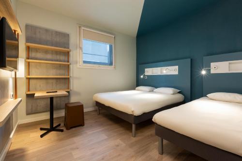 Habitación pequeña con 2 camas y escritorio. en Ibis Budget Bourgoin Jallieu Centre, en Bourgoin
