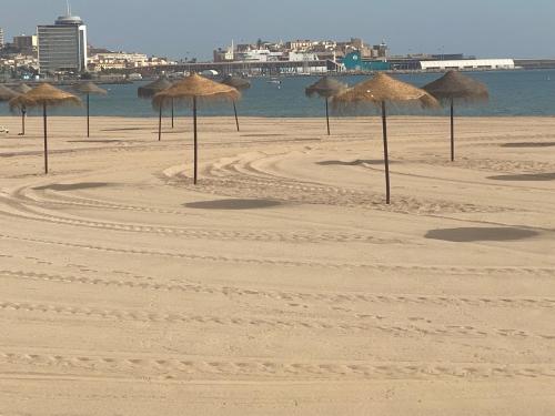 a group of straw umbrellas on a beach at Precioso apartamento a 50 metros de la playa in Melilla