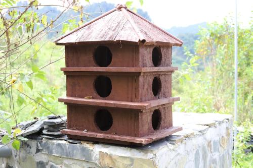 a bird house sitting on top of a stone wall at Mộc Châu Peachy Garden in An Pon