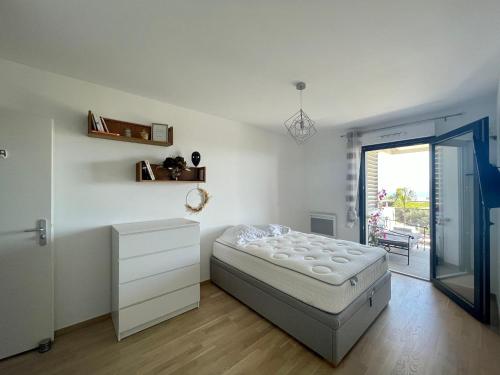 - une chambre blanche avec un lit et une porte coulissante en verre dans l'établissement T2 VUE MER - ENTREE DE VILLE, à Ajaccio