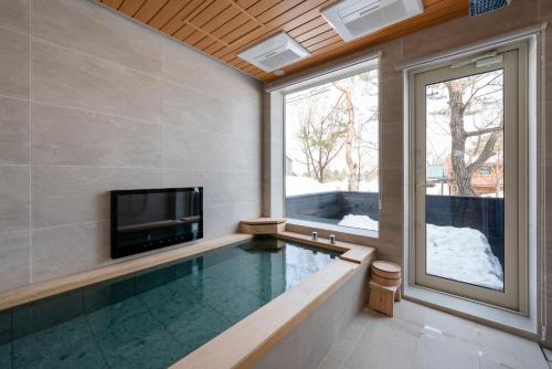 a swimming pool in a house with a tv and a window at Silver Maple Chalet by Hakuba White Fox Company in Hakuba