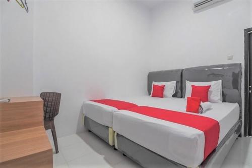 een slaapkamer met een bed met rode kussens en een bureau bij Cattail Guest House Pontianak in Pontianak