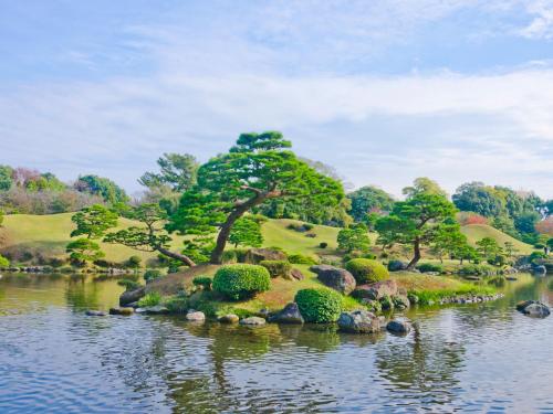 an island in the water with trees and bushes at HOTEL MYSTAYS Kumamoto Riverside in Kumamoto