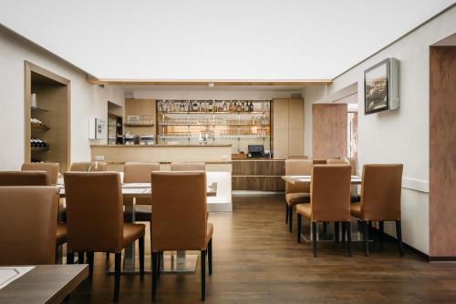 a dining room with tables and chairs and a kitchen at Hotel Richard Spa & Wellness in Mariánské Lázně