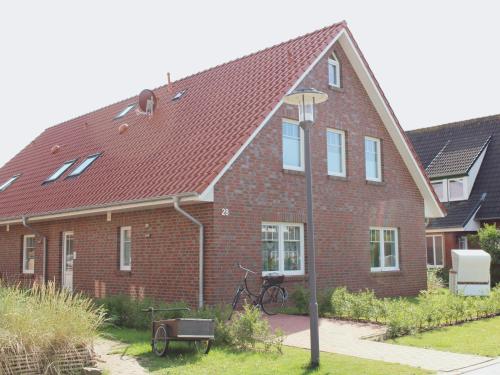 une maison en briques rouges avec un vélo devant elle dans l'établissement Heimathafen, à Langeoog