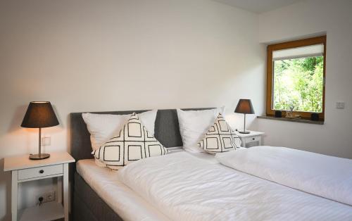 1 dormitorio con 2 camas con sábanas blancas y ventana en Apartment K13, en Bad Wiessee