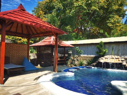 a swimming pool with a pavilion and a gazebo at Kampung Meno Bungalows in Gili Meno