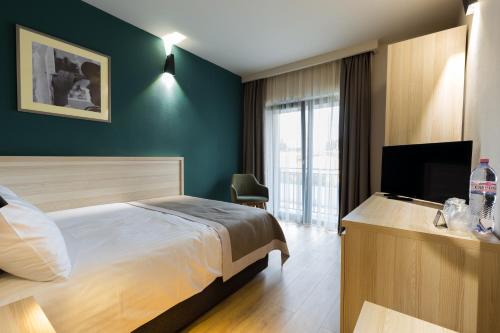 a hotel room with a bed and a television at Casa Calfelor Kolping Timișoara in Timişoara