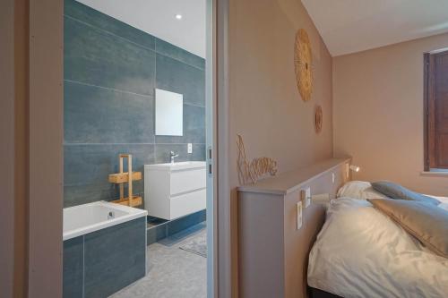 a bedroom with a bed and a tub and a sink at Gîtes Chez Oncle Nicolas in Soumagne