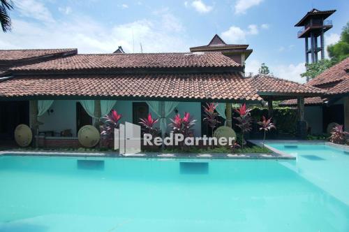 un complexe avec une piscine en face d'un bâtiment dans l'établissement Rumah Palagan Yogyakarta RedPartner, à Ngaglik