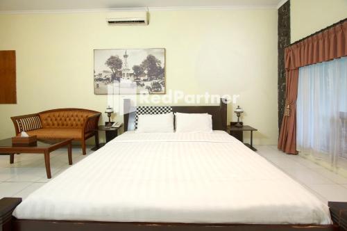 - une chambre avec un grand lit blanc et un canapé dans l'établissement Rumah Palagan Yogyakarta RedPartner, à Ngaglik