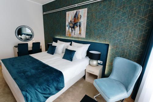 a bedroom with a bed and a blue chair at Hotel Srem in Sremska Mitrovica