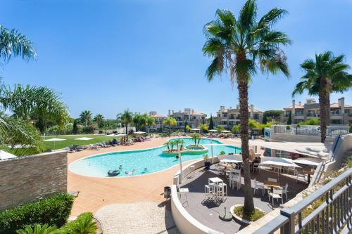 a view of a pool with palm trees and a resort at Vilamoura Pine Hills Villa in Vilamoura