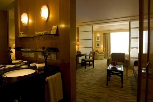 ニューデリーにあるザ グランド ニューデリーのバスルームとリビングルームが備わるホテルルームです。