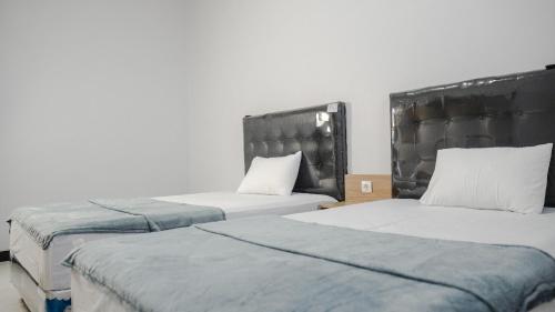 2 Betten in einem Zimmer mit weißen Wänden in der Unterkunft Sitiinggil Guest House Syariah in Tegal