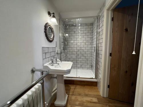 een witte badkamer met een wastafel en een douche bij Byre - Farm Cottage on 9 acre Equestrian Small Holding in Salisbury