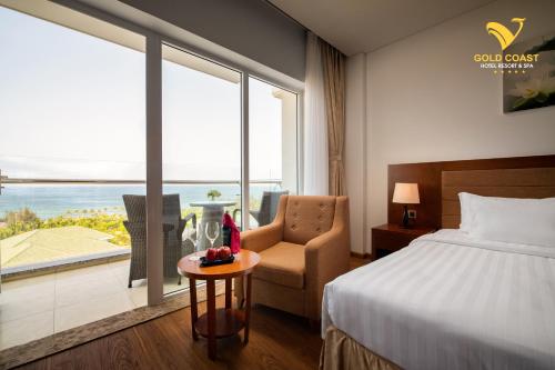 a hotel room with a bed and a chair and a window at Gold Coast Hotel Resort & Spa in Dong Hoi