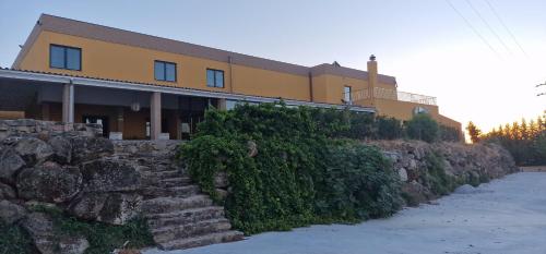 a building on a hill with a stone wall at Hotel Vila Raia in Idanha-a-Nova