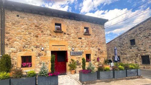 a stone building with a red door and flowers at Casa Rural Zirimiri en Herreros, Soria in Herreros