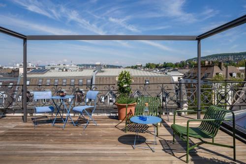 a balcony with chairs and tables and a view of a city at Alma Hotel in Zurich