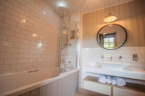 a bathroom with a sink and a tub and a mirror at High Oaks Grange - Lodges in Pickering
