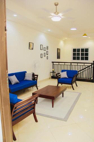 a living room with blue couches and a coffee table at Lovely 4 Bedroom Solar Powered House with CCTV and Unlimited WiFi near Devtraco Court Community 25 Tema in Tema