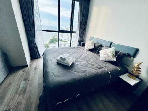 a bedroom with a black bed with a large window at Unique 1-BR w/Seaview Balcony and Onsen in Pattaya in Pattaya South