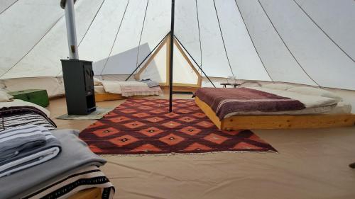 - une chambre avec un lit et un tapis dans une tente dans l'établissement Dolina Village Glamping, à Zece Hotare
