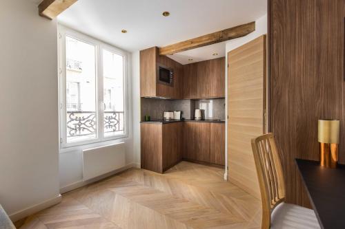 a kitchen with wooden cabinets and a window at CMG- Charming appartement 2P - Batignolles in Paris
