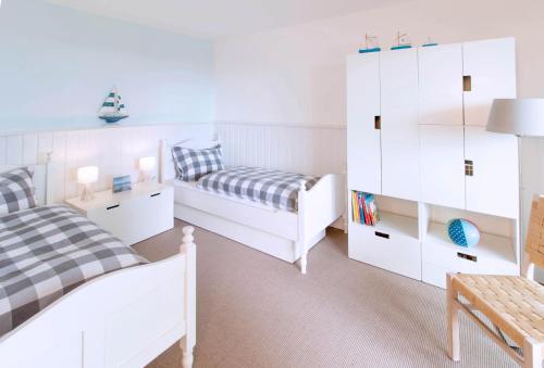 1 dormitorio blanco con 2 camas y vestidor en Ferienhaus Großes Meer, en Bedekaspel