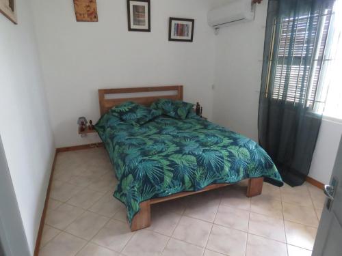 Bett mit grüner Decke in einem Schlafzimmer in der Unterkunft VILLA CANELLE in Trou aux Biches