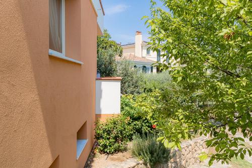 a building with a window next to a yard with plants at Villa Caterina in La Maddalena