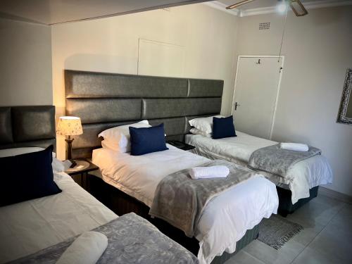 Cette chambre comprend 3 lits avec des oreillers bleus. dans l'établissement Lemon Rose Guest House, à Virginia