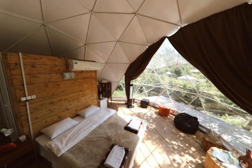 a bedroom with a bed and a large window at Elsesi Racha Glamping in Ambrolauri