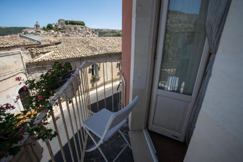 a white chair sitting on a balcony next to a door at Bed and Breakfast Terra del Sole Ibla in Ragusa