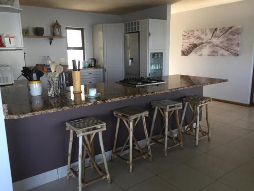 a kitchen with a counter and bar stools at St Francis Bay House On The Canal in St Francis Bay