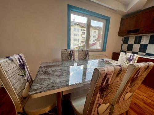 cocina con mesa con sillas y ventana en CASA CU LAVANDĂ, en Vatra Dornei