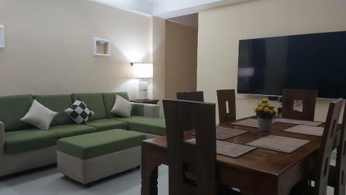 a living room with a green couch and a table and a television at Anna Asia Villa in Kandy