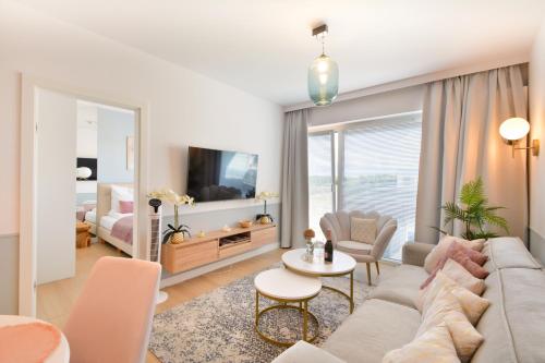 a living room with a couch and a tv at Klif Apartamenty Polanki Aqua in Kołobrzeg