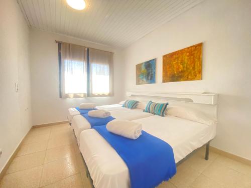 um quarto com quatro camas com lençóis azuis e brancos em Villa Paulina em Sant Martí d’Empúries